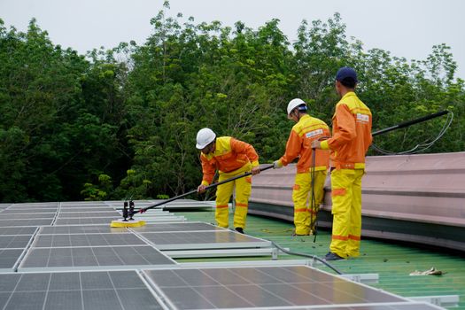 Huiseigenaar reinigt zonnepanelen veilig met een zachte borstel op het dak van een woning