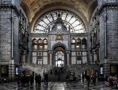 Antwerpen centraal weer rond de hoofdingang aan het Koningin Astridplein met reizigers onder paraplu's